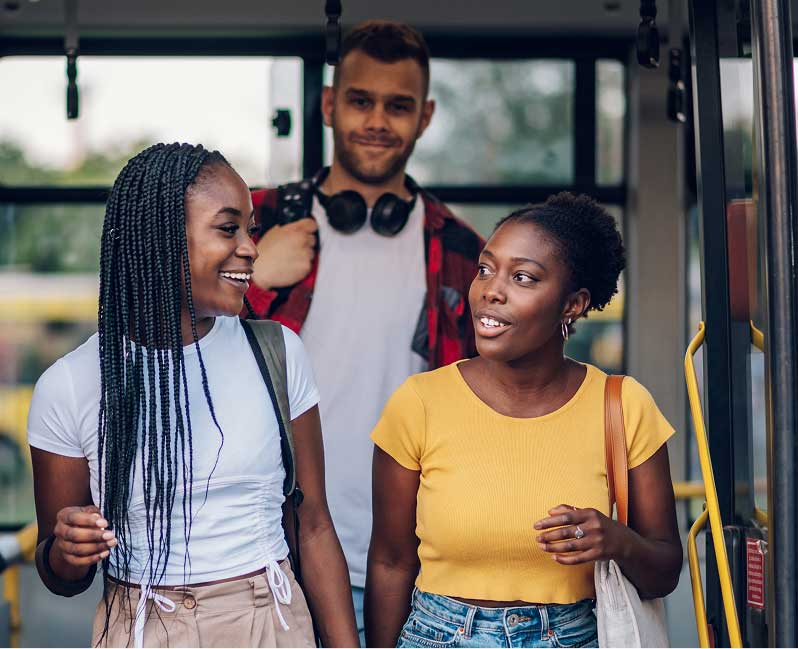 A man and two women are standing next to each other while exiting a bus